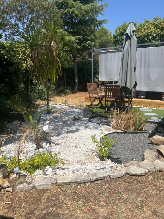 a patio with an umbrella and a table and bench at Cosy house studio in Saint-Aunès