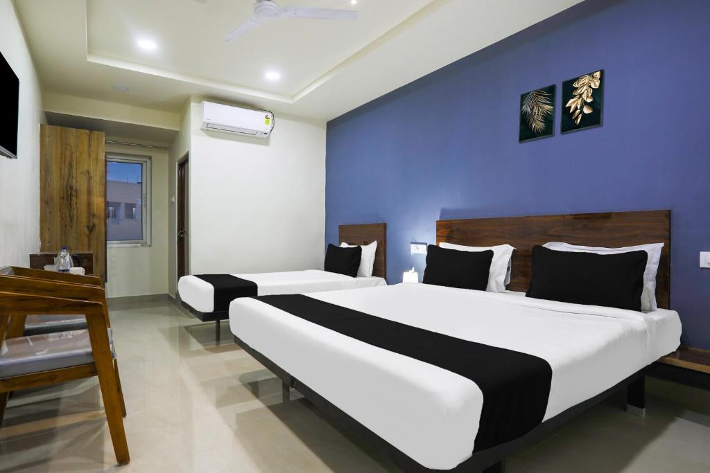 a bedroom with two beds and a blue wall at Townhouse RIO in Hyderabad