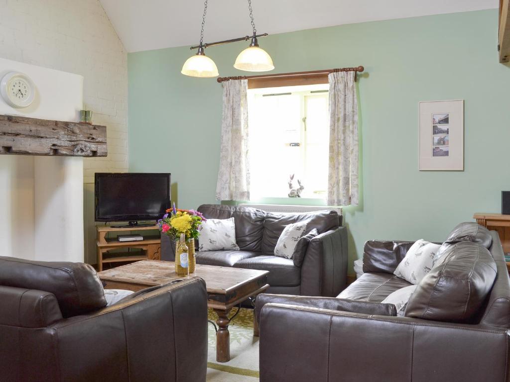 a living room with leather couches and a television at Riverview - Ioj in Brandesburton