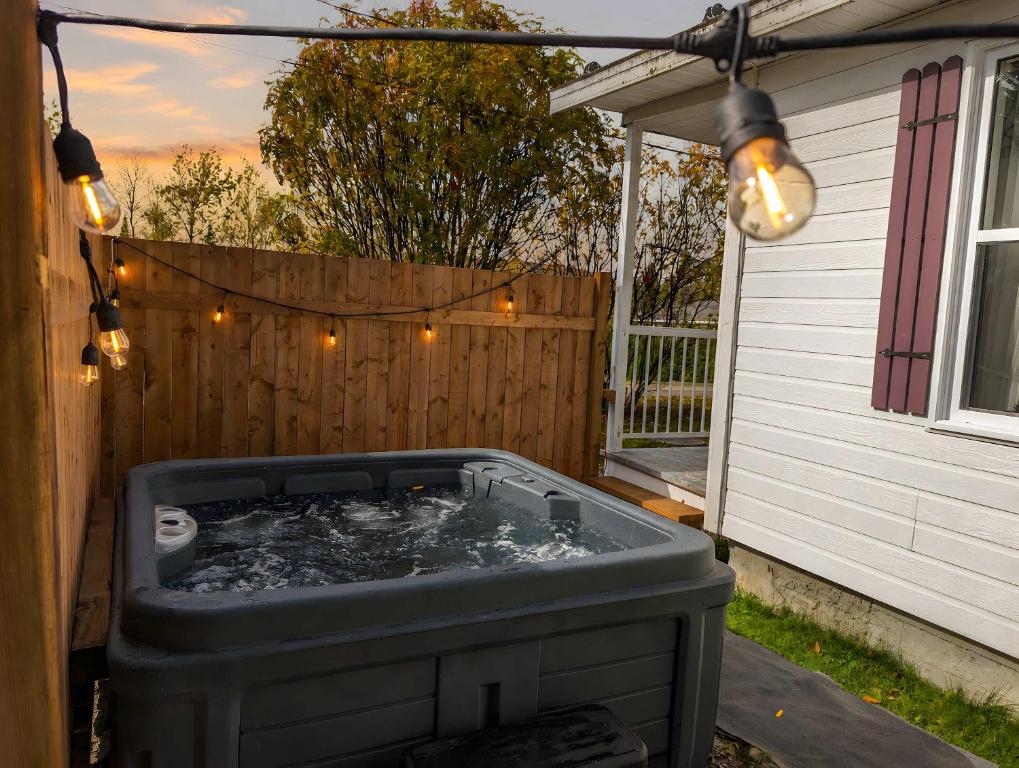 a hot tub in a backyard with lights and a fence at Cozy and Welcoming Chalet with Spa in Saint-Tite-des-Caps