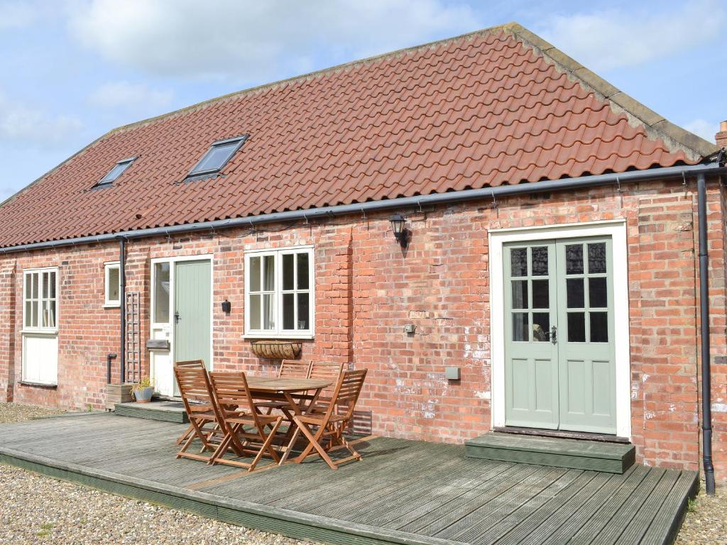 a brick house with a table and chairs on a wooden deck at Broad Leaf - Iok in Brandesburton