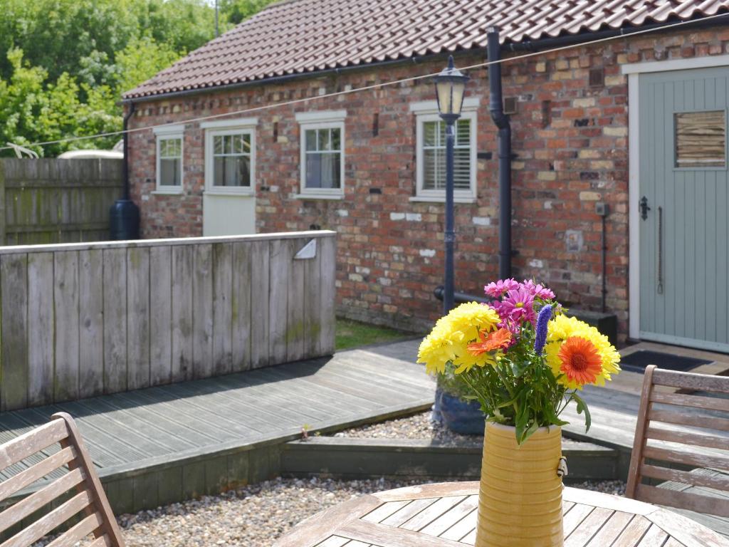 a vase of flowers sitting on a table in front of a house at Meadow View - Iom in Brandesburton