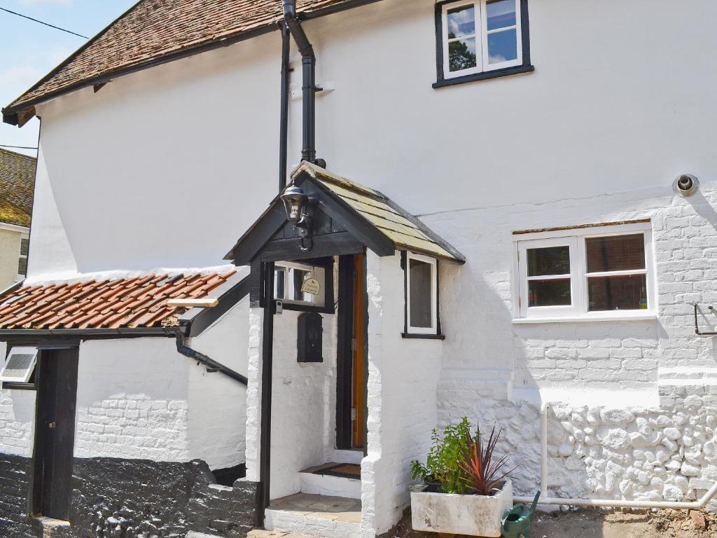 a white house with a black door on the side of it at Walnut Cottage in Sproughton