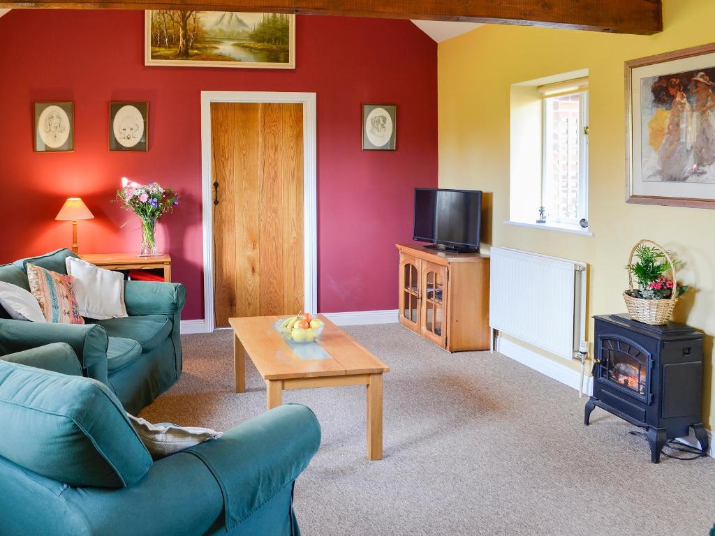 a living room with a couch and a tv at Barleycorn in Holwell