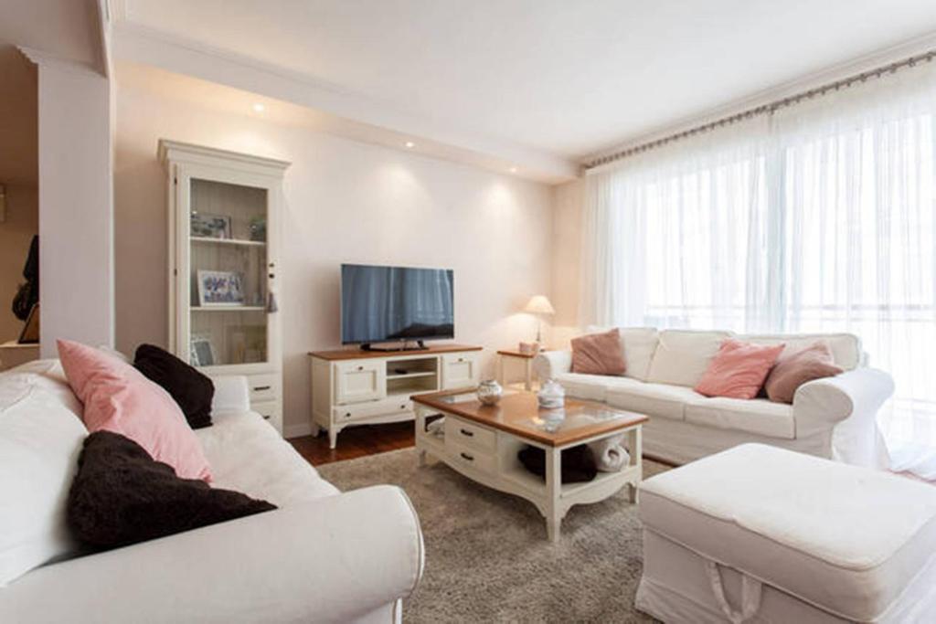 sala de estar con muebles blancos y TV de pantalla plana en Lovely Loft Rambla, en Alicante