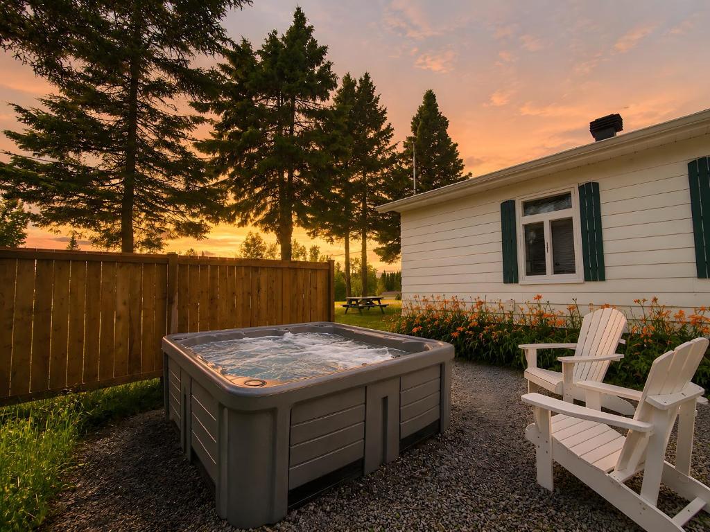 a hot tub in a yard next to two chairs at WOW Chalet Boho - Charlevoix Spa Firepit and BBQ in Saint-Tite-des-Caps