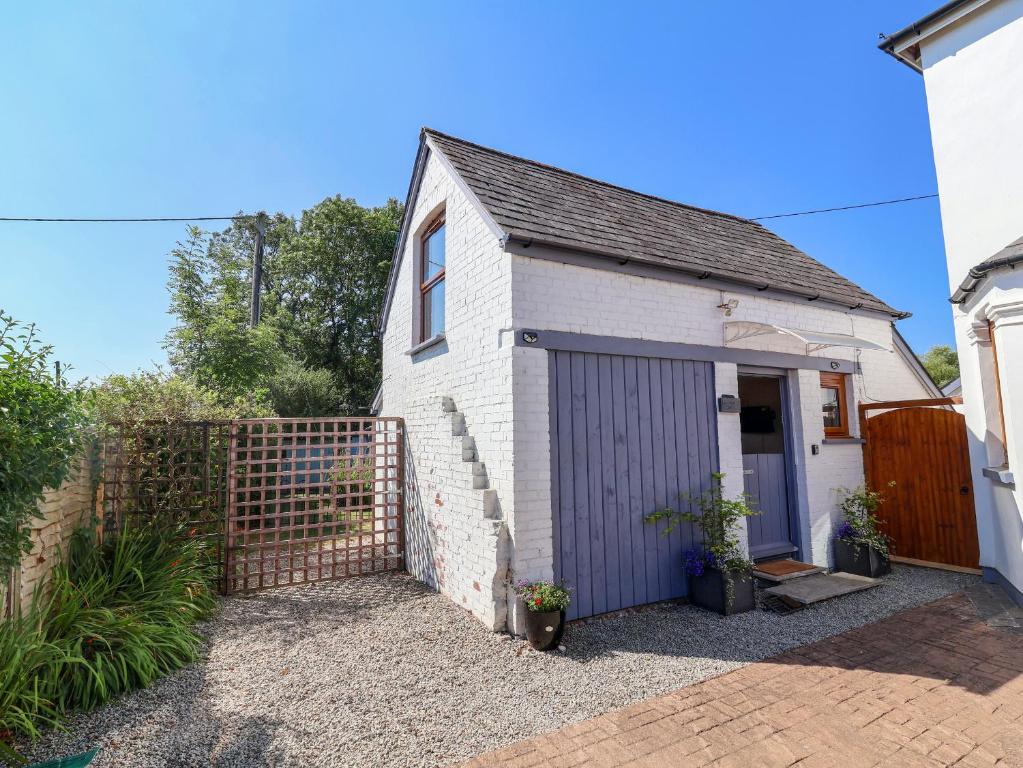 a small white house with a purple garage at Coach House in Beaworthy