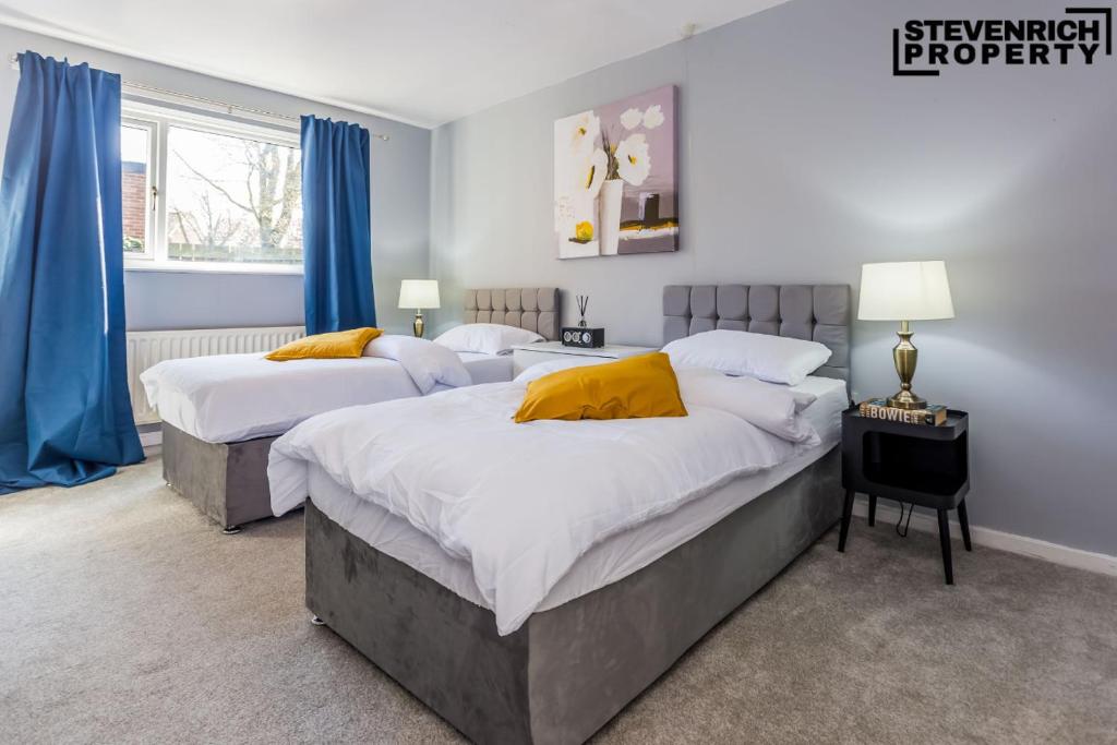 two beds in a bedroom with blue curtains at Newly Refurbished Flat Parking 2 Bedrooms 4 Guests in Kenton