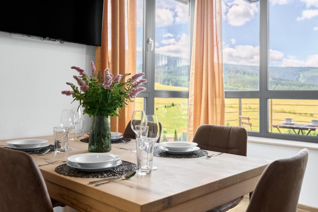 a dining room table with a vase of flowers on it at Enzian by Mountain ways in Loučná pod Klínovcem