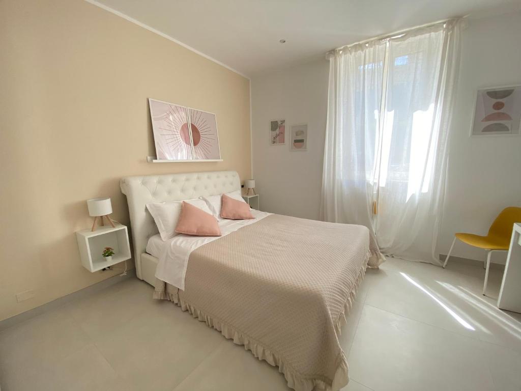 a white bedroom with a bed with two pink pillows at Il Rifugio in Sulmona
