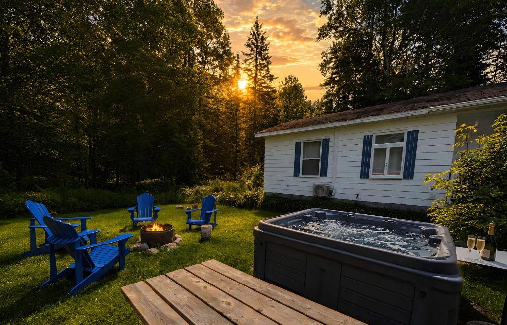 a backyard with a hot tub and a table and chairs at Nature Chalet with Private Spa & Firepit in Saint-Tite-des-Caps