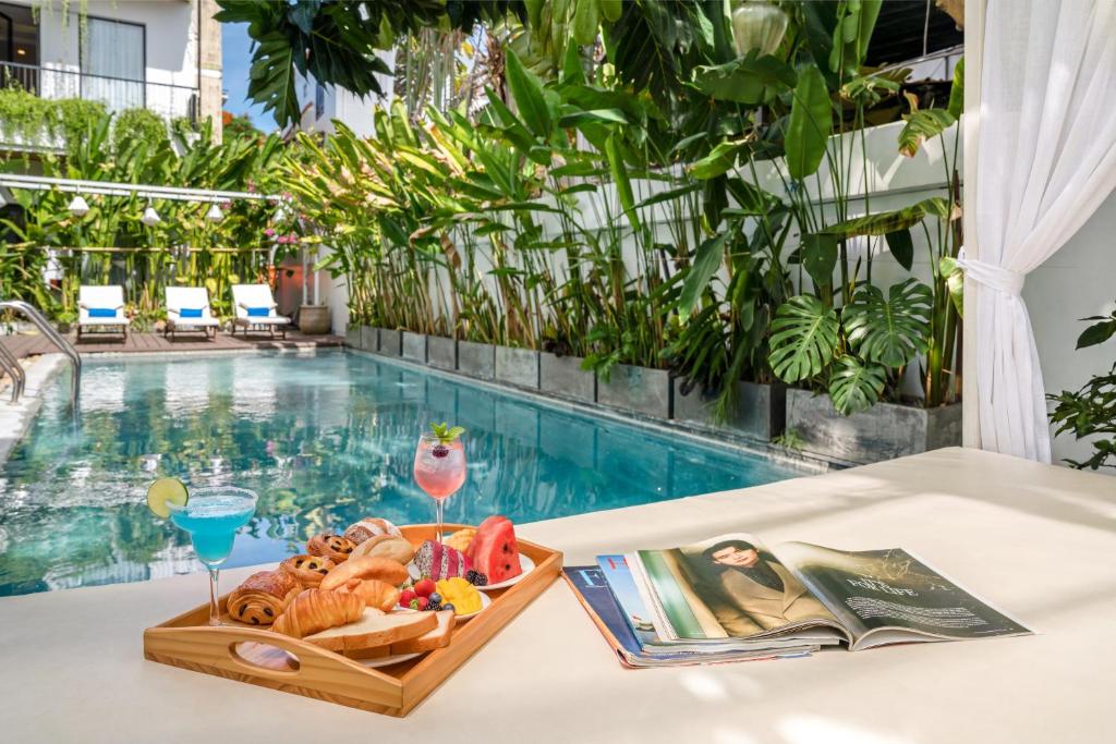 a tray of food on a table next to a swimming pool at Flora Hoi An Lantern Town in Hoi An
