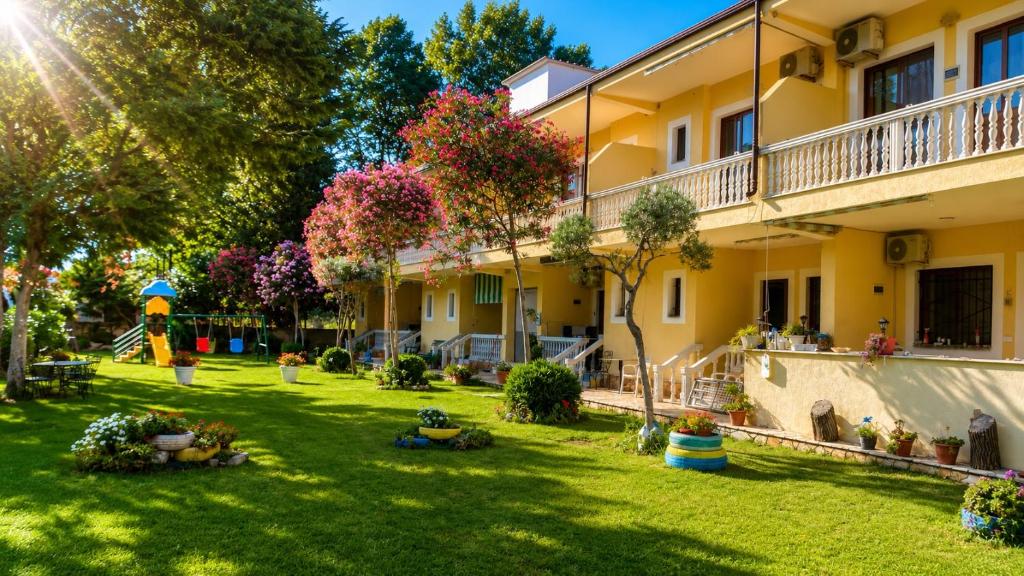 a yard of a building with trees and flowers at Hotel Marino in Baks-Rrjoll