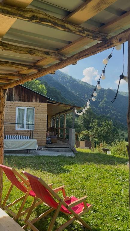 a couple of chairs sitting on the grass in front of a house at Chalet Gveleti in Barisakho