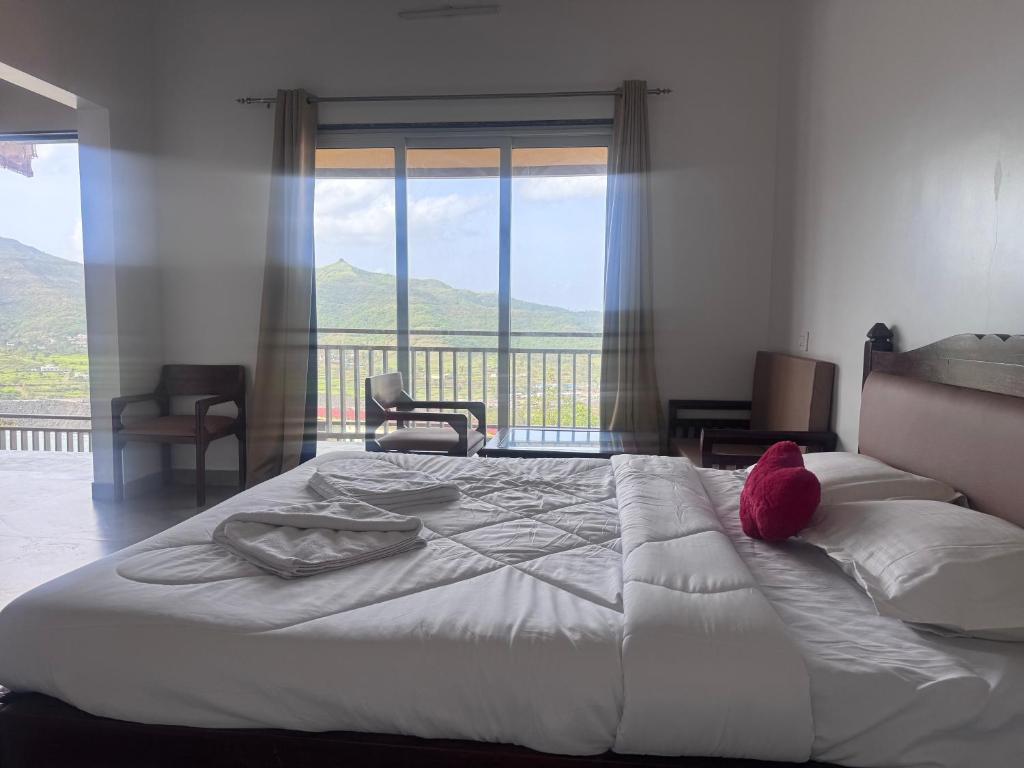 a bedroom with a large bed with a large window at Jashoda Dham Agro Tourism in Pune