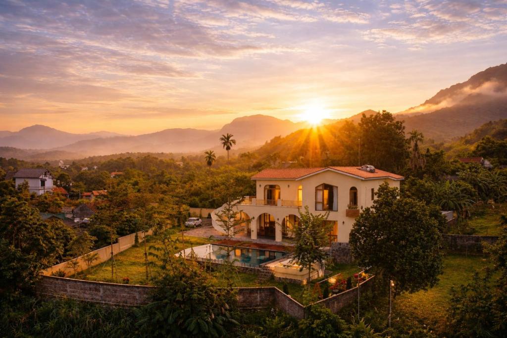 a villa with a swimming pool in front of a sunset at The Windy Villa Ba Vì in Xóm Gốc Gia