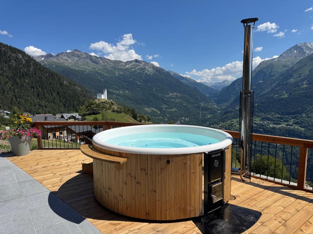 a hot tub on a deck with a view of mountains at Chalet Evidence, chalet d'hôtes in Montvalezan