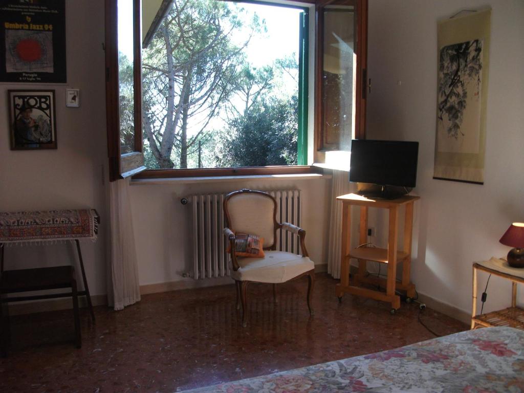 - une chambre avec une fenêtre, une chaise et une télévision dans l'établissement B&B La Principessa, à Corciano
