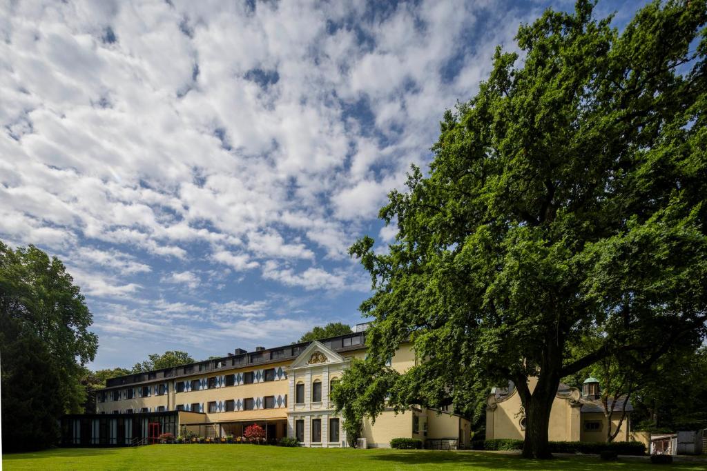 a large building with a tree in front of it at Parkhotel Hohenfeld Münster in Münster