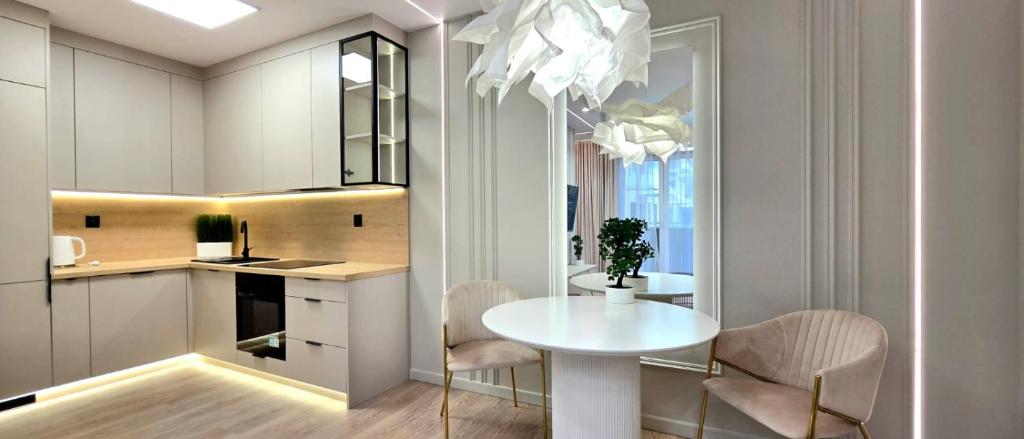 a white kitchen with a white table and chairs at Apartament Dąbrowskiego in Iława