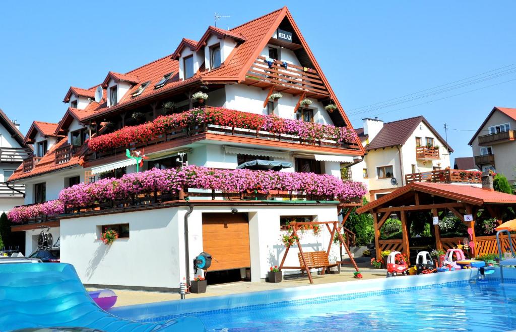 a house with flowers in front of a swimming pool at Pensjonat Relax in Mikołajki