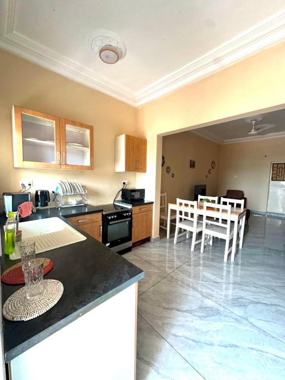a kitchen and living room with a table and chairs at KMR Apartment - Sira in Sere Kunda