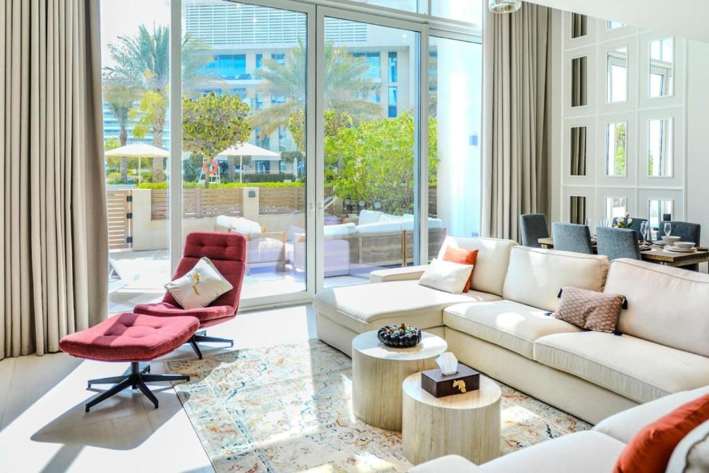 a living room with a white couch and a red chair at Aurora 1BR - Coastal Chic Luxe Retreat in Abu Dhabi