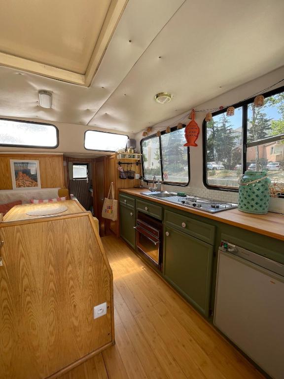 a kitchen with green cabinets and a wooden floor at Bateau Erebus - Bohême chic in Narbonne