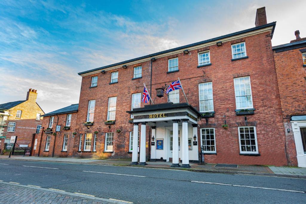 a large brick building with two american flags on it at The Wynnstay Hotel, Oswestry, Shropshire - The Coaching Inn Group in Oswestry
