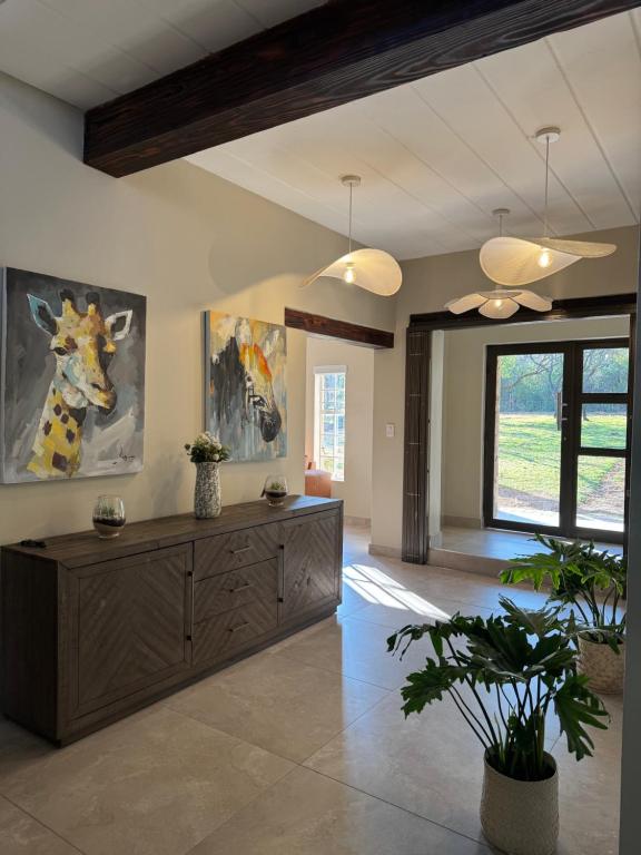 a living room with a wooden cabinet and a painting of a giraffe at Villa Euris Guesthouse in Brits