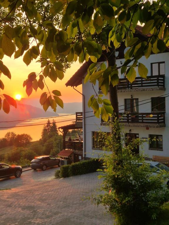 a building with a car parked in front of a sunset at Pensiunea La Bunica in Rugineşti
