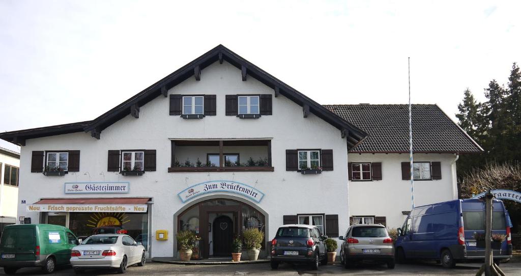 a white building with cars parked in front of it at Landgasthof zum Brückenwirt in Starnberg