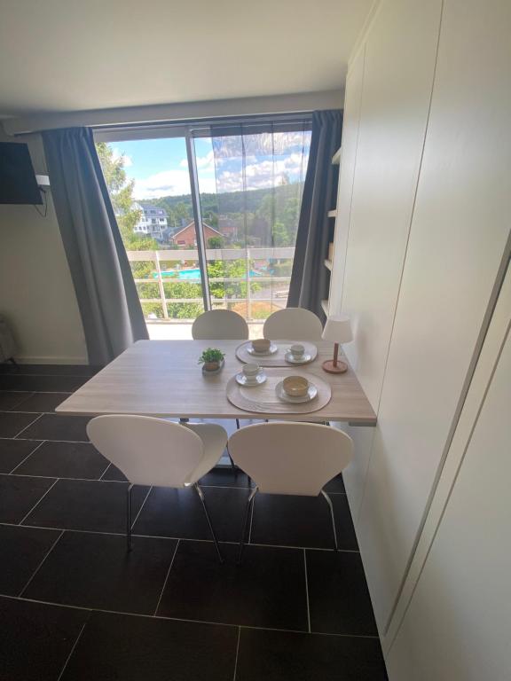 a dining room with a table and chairs and a large window at Studio Cosy 2 in Han-sur-Lesse