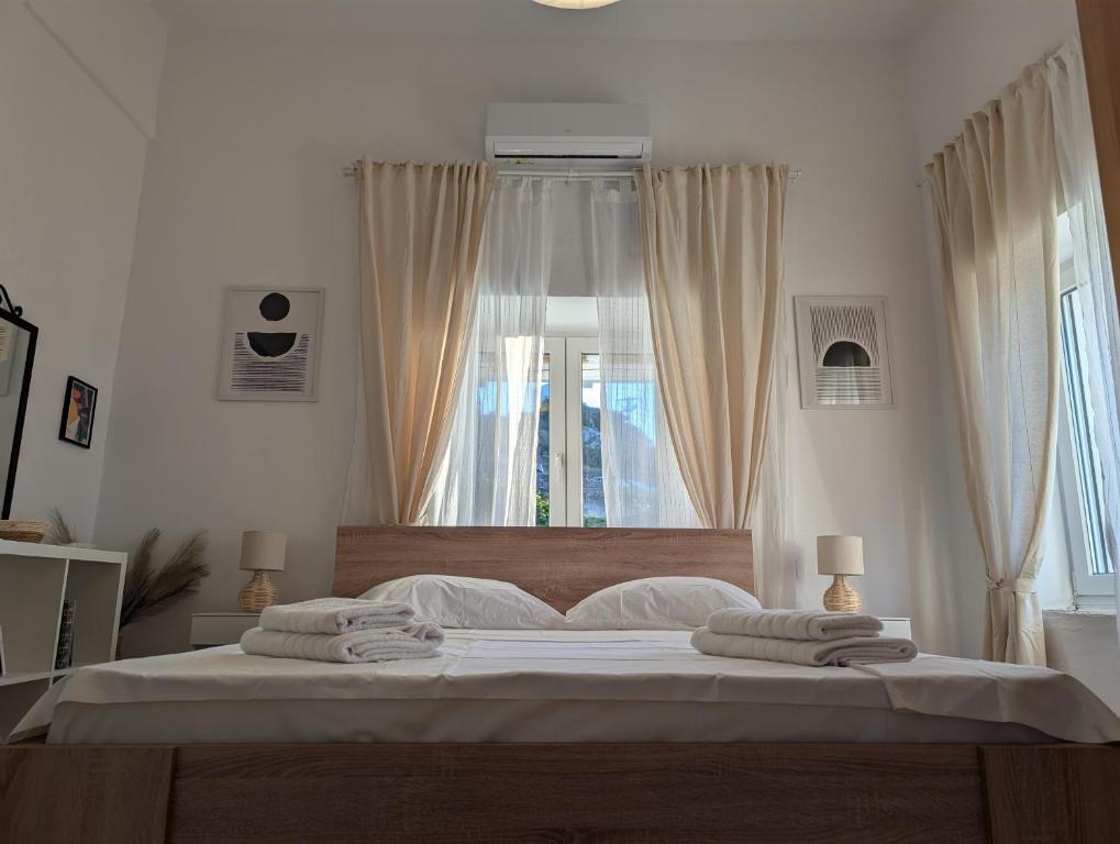 a white bedroom with a large bed with towels on it at Theros House in Ioulis