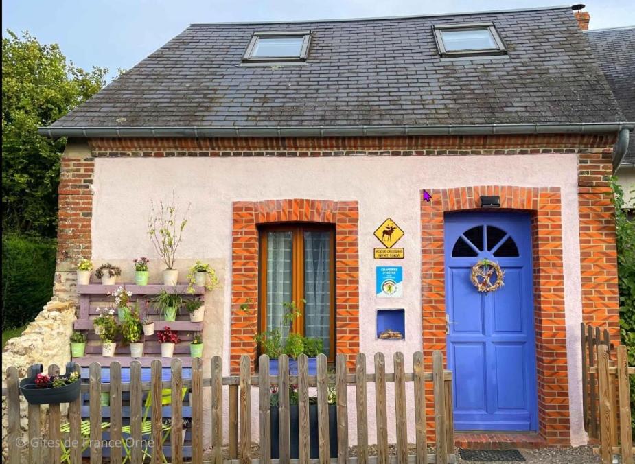 a small house with a blue door and a fence at L'Érable du perche in Tourouvre