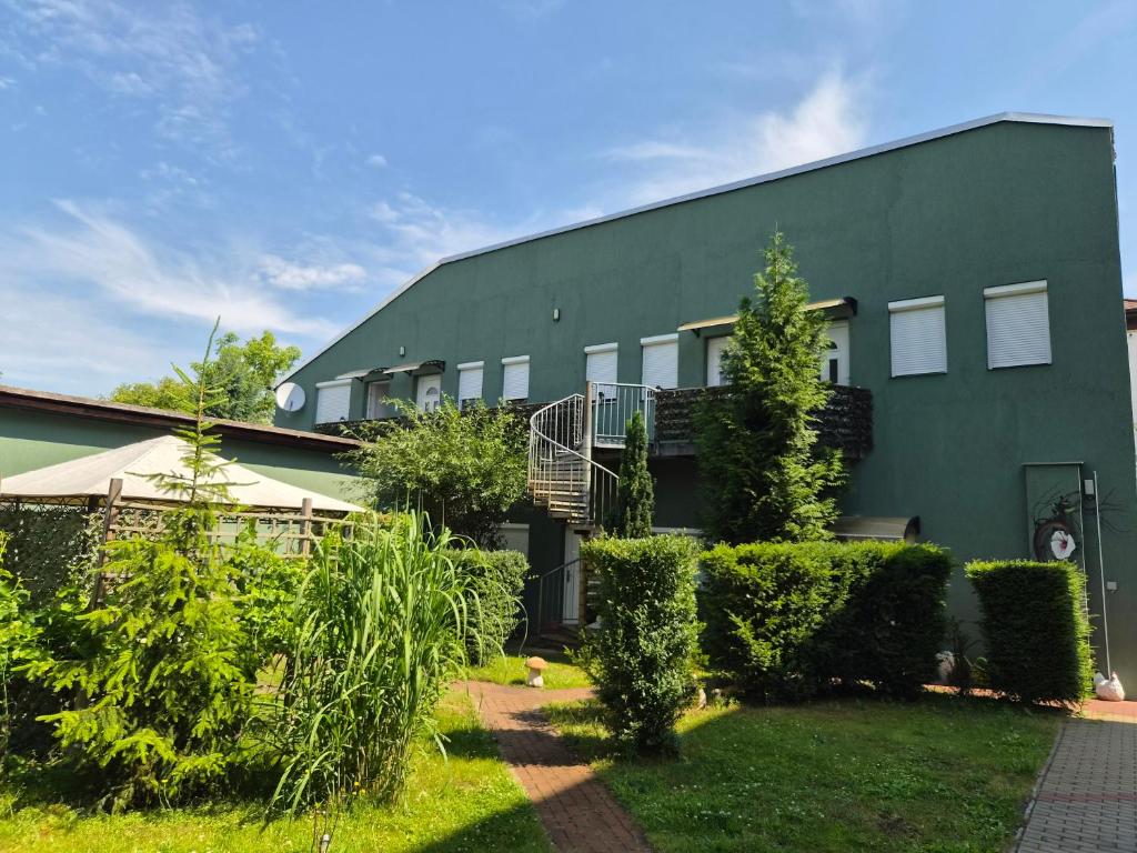 a green building with bushes in front of it at Neu!!! Pension Scherz-ruhig am Standrand mit Wasserzugang & Paddelboot in Lübbenau