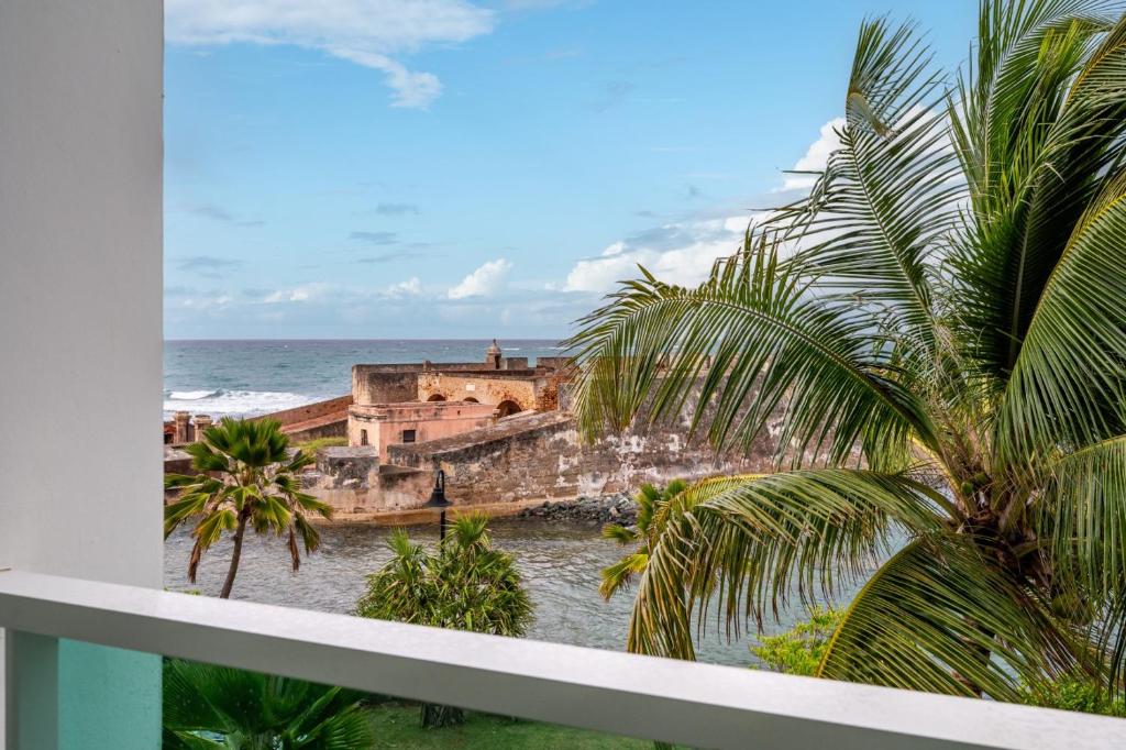 a view of the ocean from a balcony with palm trees at Designer Oceanview Penthouse & Pool - Condado in San Juan