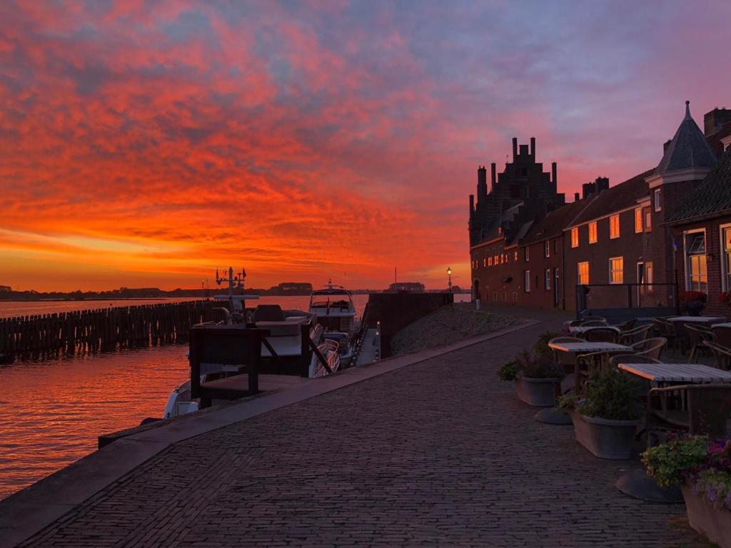a sunset over a brick walkway next to a body of water at Hotel Noorderhoofd in Veere