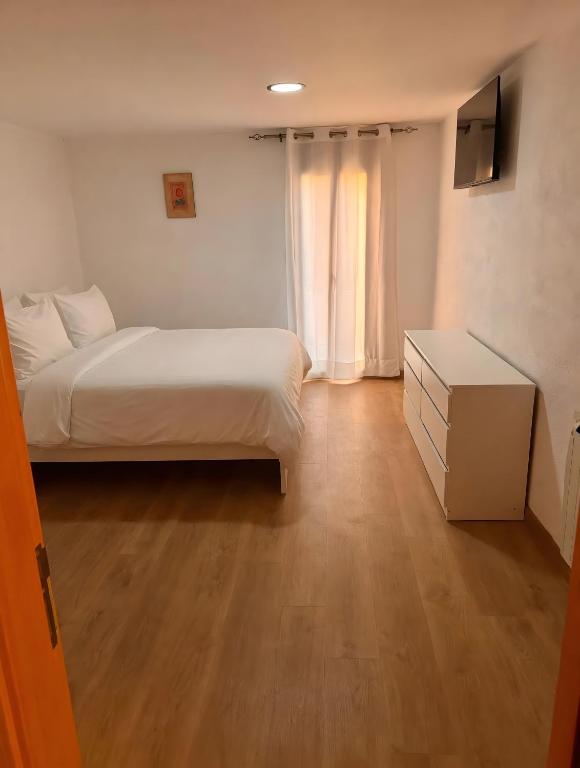 a small bedroom with a bed and a dresser and a television at Ca la Selma in Aiguamurcia