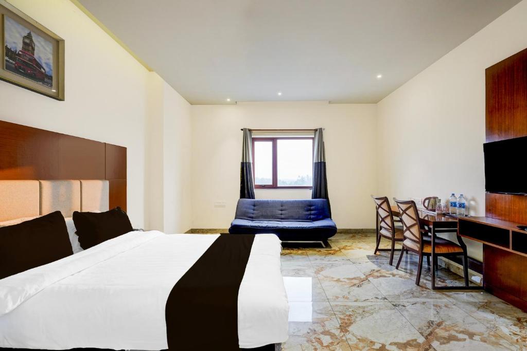 a bedroom with a large bed and a table and chairs at Townhouse JFN Comfort Hotel in Chennai