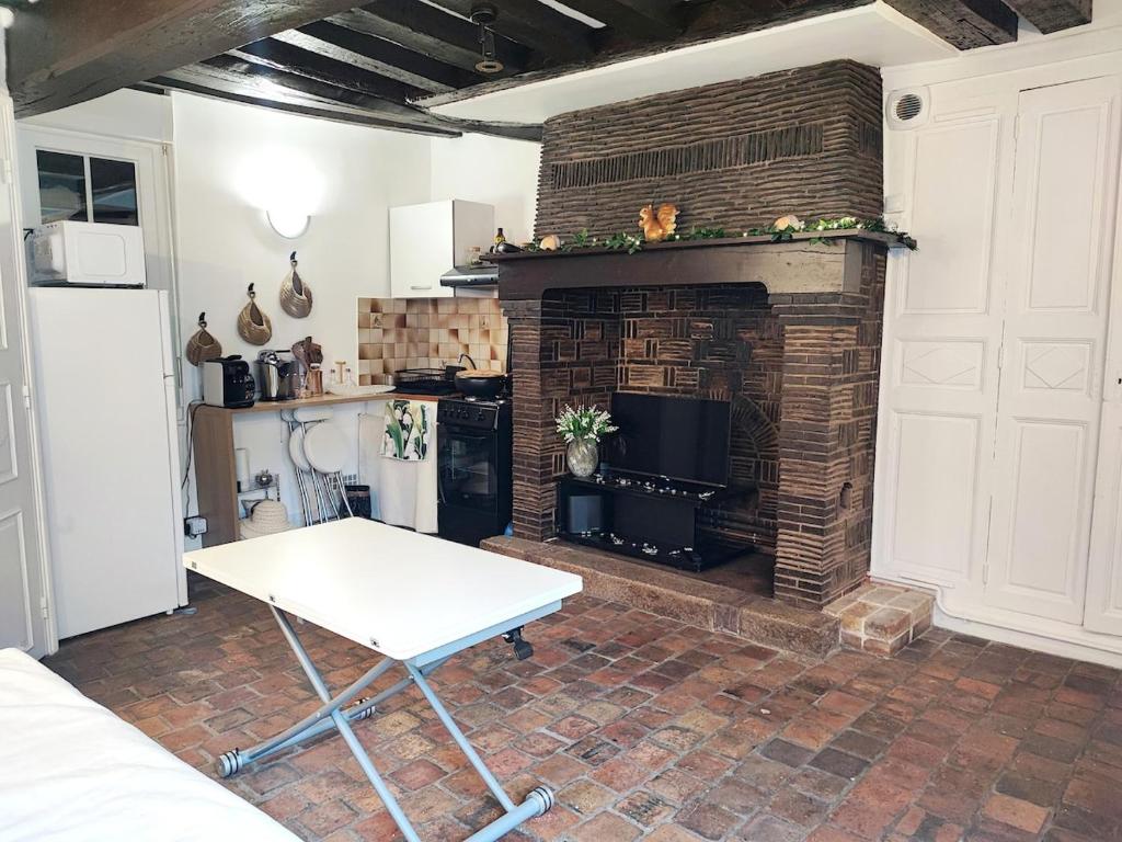 a living room with a table and a fireplace at Cottage spirit in Normandy - typical studio in Évreux