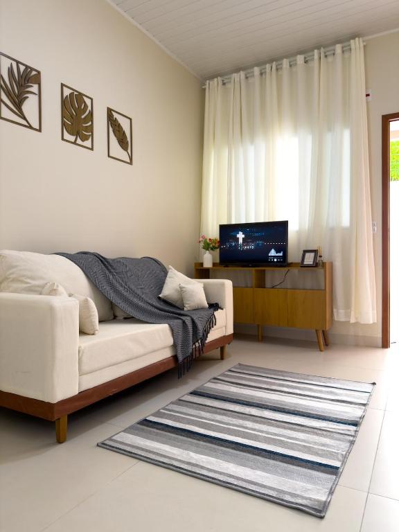 a living room with a white couch and a television at Casa 02 - Aconchegante e cheia de estilo - 5 min do centro in Alta Floresta