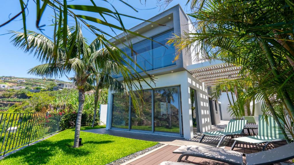 a house with a palm tree in front of it at Villa Calhau by LovelyStay in Ponta do Sol