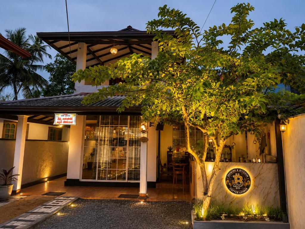 a building with a tree in front of it at Skyline & bitcoin coffee lodge in Kalutara