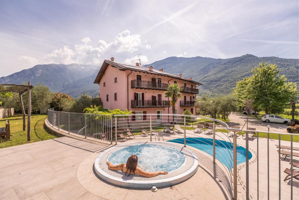 a woman laying in a pool in front of a house at Residence La Vigna in Arco