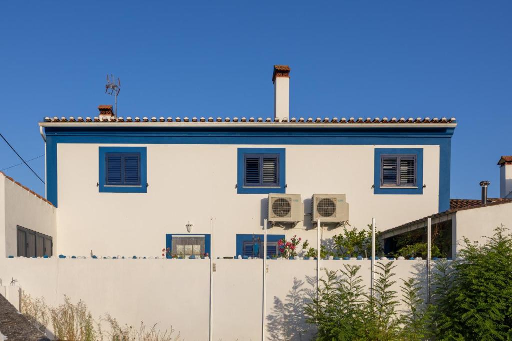 a white building with blue windows and a fence at Casa de Sume in Monte da Pedra