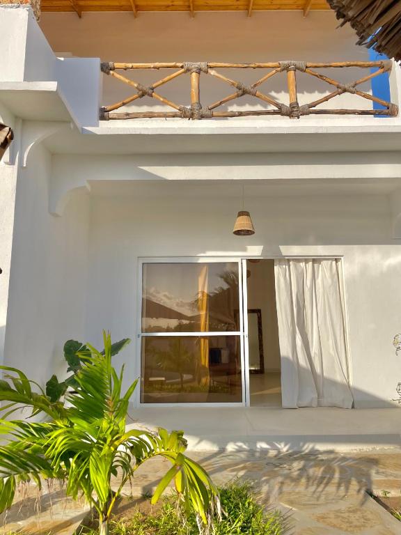 a white house with a glass door and a window at Deluxe room in Watamu