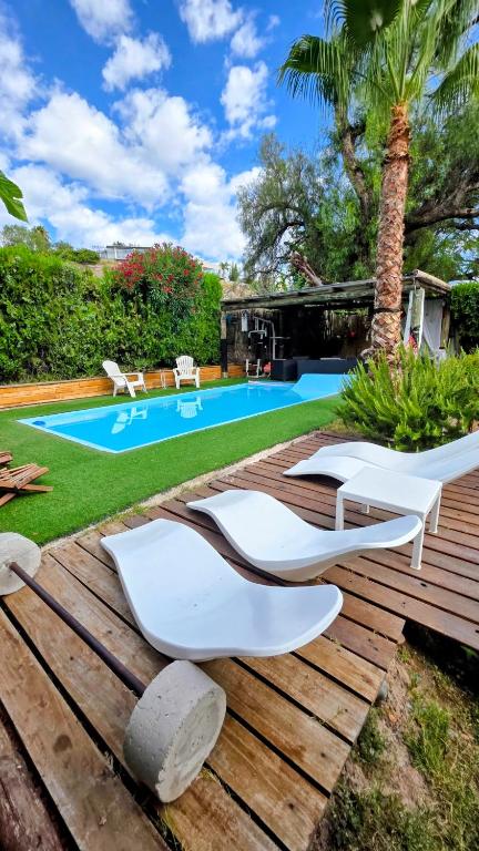 a group of white chairs on a wooden deck near a swimming pool at Lodi House in Godoy Cruz