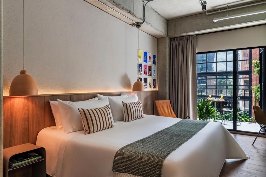 a bedroom with a large bed and a large window at Obra Hotels in Medellín