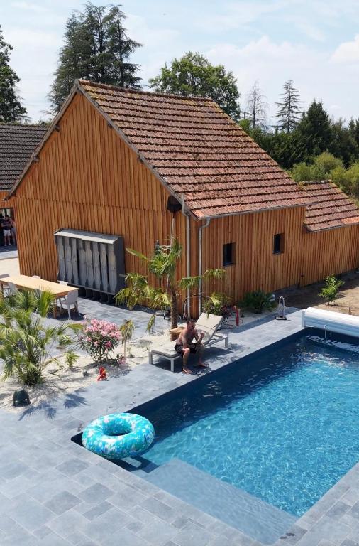 a swimming pool in front of a building with a house at Chambre d'hôtes Cocotte & Bigoudi in La Ferté-Beauharnais